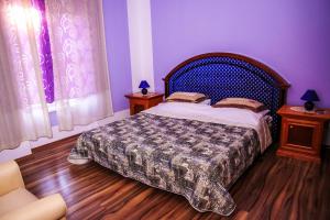 里耶卡水晶罗切客房的一间卧室配有一张紫色墙壁和木地板的床。