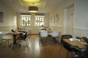 TessenderloBed & Breakfast De Kleine Magnolia的配有木桌和白色椅子的餐厅