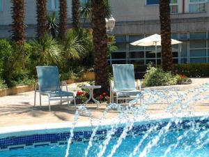 维拉弗兰卡宾纳戴斯Hotel Air Penedès的游泳池旁的两把椅子和一把遮阳伞