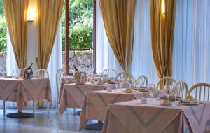 伊斯基亚圣吉凡尼特尔米酒店的用餐室配有桌椅和黄色窗帘