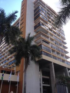 巴西利亚MIX APART Hotel的一座高大的建筑,前面有棕榈树