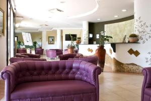 伊索拉迪卡波里祖托Villaggio Spiagge Rosse的一间设有紫色皮革沙发的等候室和一个沙龙