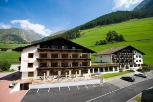 塞纳莱斯Berghotel Tyrol的一座大酒店,后面是一座绿色山丘