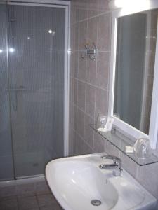 Bernières-sur-Mer吕泽尔恩宾馆的浴室配有盥洗盆和带镜子的淋浴