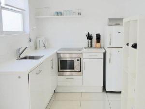威廉斯塔德Appartement Chandon 4 pers的白色的厨房配有水槽和微波炉