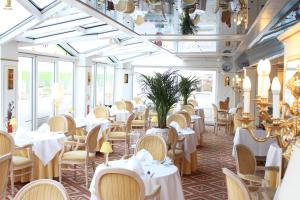 库克斯港斯坦乐酒店的餐厅设有白色的桌椅和窗户。