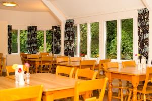 格拉斯米尔国际青年旅社格拉斯米尔博瑟利豪酒店的餐厅设有木桌、椅子和窗户。