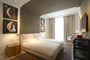巴塞罗那城中公寓的卧室配有白色的床和窗户。