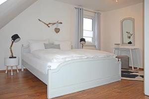PantowFerienhaus Rügen的卧室配有白色床单和白色床。