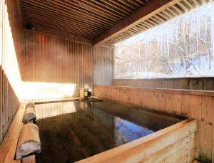 轻井泽小濑温泉酒店的一座带窗户的木屋内的游泳池
