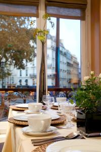 巴黎玛索香榭丽舍酒店的桌子上带盘子和盘子的桌子,有窗