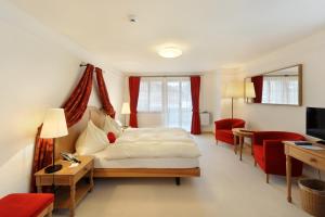 格施塔德格施塔德贝勒里夫酒店的一间卧室配有一张床、一张桌子和红色椅子
