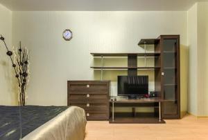 沃罗涅什ATLANT Apartments 106的一间卧室配有一张桌子、一台电视和书架