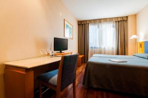 瓦伦西亚维拉卡洛斯酒店的酒店客房配有书桌和床。