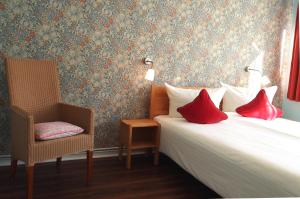 不莱梅布莱梅伽斯特豪斯酒店的一间卧室配有一张带红色枕头的床和一把椅子