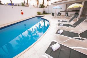 巴西利亚维罗那哈普拉斯长住公寓式酒店的一个带椅子和遮阳伞的游泳池