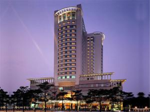 汕头汕头君华海逸酒店的一座高大的建筑,前面有树木