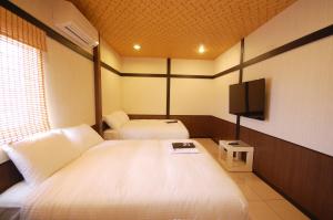 恒春古城花野井的酒店客房设有两张床和一台平面电视。