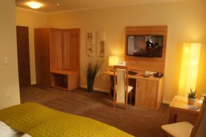 吕贝克库勒帕兰德酒店的一间卧室配有一张床和一张书桌及电视