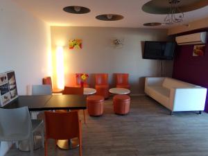 帕拉瓦莱弗洛蒙彼利埃南部海滩酒店的一间配备有橙色椅子、桌子和沙发的等候室