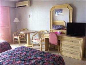 塔穆宁图蒙海湾船长酒店的一间卧室配有书桌、一张床和镜子
