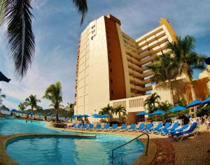 马萨特兰拉斯弗洛雷斯海滩度假村酒店的一个带游泳池和椅子的度假胜地和一座建筑