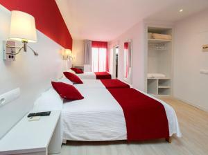 圣安东尼奥马力诺旅馆的一间卧室配有两张带红色枕头的床