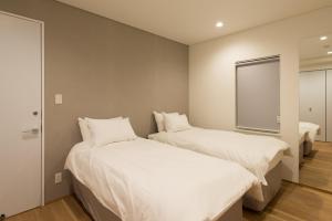 二世古优苏基小木屋的配有白色床单和窗户的客房内的两张床