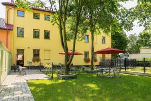 弗罗茨瓦夫布罗池餐厅酒店的院子内带桌子和遮阳伞的黄色建筑