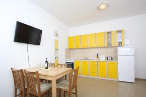 诺瓦利娅Apartments Jasmina的一个带木桌的厨房和一个带黄色橱柜的厨房