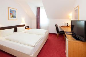 德累斯顿伽登乡村小别墅公寓式酒店的配有一张床和一台平面电视的酒店客房