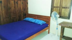 婆罗浮屠格利亚哈尔佳民宿的一张带蓝色枕头的床和一个风扇