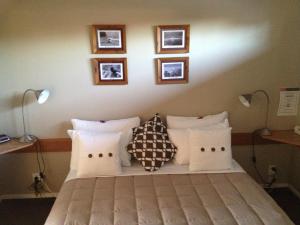 蒂阿瑙湖畔旅馆 的一间卧室配有一张带枕头的床,墙上挂有图片