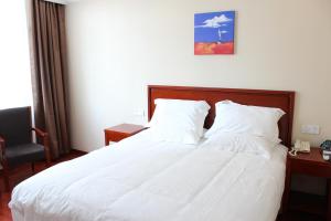 松江格林豪泰上海市松江松东商务酒店的一间卧室配有一张带白色床单和椅子的床