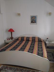 布加勒斯特海尔维半岛酒店的一间卧室配有一张床和一张带台灯的桌子