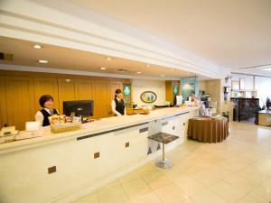 高知South Breeze Hotel Kochi Kaigetsu的两名妇女站在厨房的柜台上