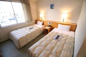 高知South Breeze Hotel Kochi Kaigetsu的酒店客房设有两张床和窗户。