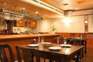高知South Breeze Hotel Kochi Kaigetsu的一间带木桌和椅子的餐厅和一间酒吧