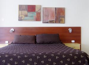 布兰卡港Apartamentos Güemes - Monoambientes的一间卧室配有一张床铺,上面有两幅画