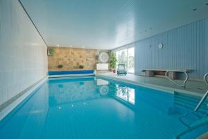 圣安德里斯伯格兰德豪斯菲舍尔酒店的一座带蓝色瓷砖墙的大型游泳池