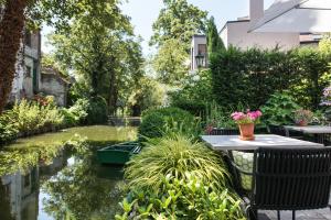 布鲁日国王之家住宿加早餐酒店的花园设有池塘和桌椅