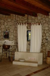 VátosMusician's Round House & Castello的石头浴室设有浴缸和淋浴帘