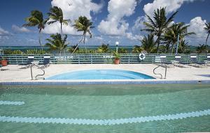 克里斯琴斯特德圣克罗伊海滩俱乐部网球度假酒店的一个带椅子的游泳池,背景是大海