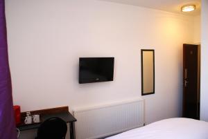 哈罗The Hindes Hotel的卧室设有壁挂式电视和床。