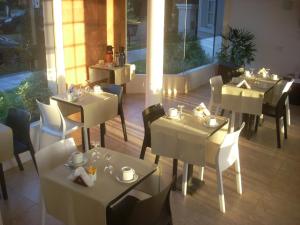 科隆Hotel Queguay的一间餐厅,房间内设有白色的桌椅