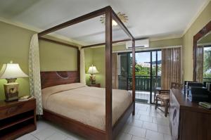 克里斯琴斯特德殖民湾海滩度假村的一间卧室设有一张天蓬床和一个阳台