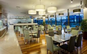 布里斯班布里斯班机场诺富特酒店的餐厅设有桌椅和窗户。