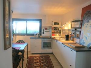 多维尔舒适精装公寓的厨房配有白色橱柜、桌子和窗户。