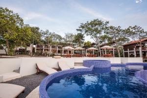 La LagunaPacaya Lodge and Spa的度假村的游泳池,配有椅子和遮阳伞