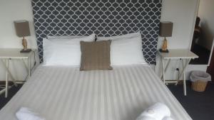 Fish Creek鱼溪酒店的卧室配有一张带两张桌子的大型白色床